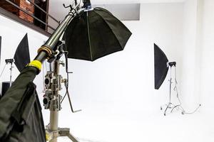 Empty photo studio with lighting equipment. Photographer workplace interior with professional tool set gear. Flash light white background scenes ready for studio shooting. Modern photographer studio