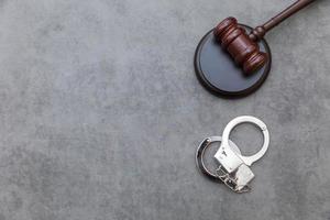 Law theme. Court of law trial in session. Judge gavel handcuffs on grey table in lawyer office or court session. Mallet of judge on concrete stone grey background. Justice human rights concept. photo