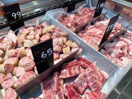 diferentes partes de la exhibición de carne de cerdo en el supermercado. hay una etiqueta de precio en idioma tailandés. carne fresca refrigerada y buen material de cocina. foto