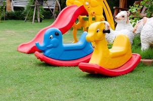 Colorful plastic rocking horse in playground. Lay on green grass background. photo