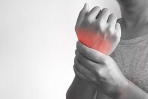 Closeup of asian male arms holding his painful wrist caused working hard on the computer, laptop. Office syndrome hand pain by occupational disease. Arthritis, neurological disease concept. photo