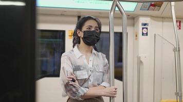 suporte feminino asiático atraente e segurando poste de metrô para equilibrar dentro do estilo de vida urbano da cidade de skytrain do metrô durante a pandemia de covid-19, novo normal no transporte público, distância social