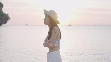 Young beautiful asian woman feel sad walking alone on the beach seashore with horizon seascape sky during sunset golden hour, loneliness heart broken feeling, lonely vacation, warm tropical climates. video