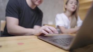 Female blonde manager mentor listening on male asian intern new employee explaining online strategy on laptop, talking to colleague teammate working together instructing cooperating in office video