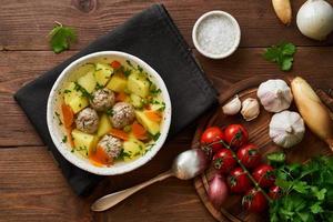 meatballs soup in white plate on old wooden rustic brown table, top view photo
