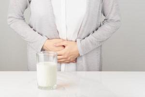 Woman next to glass of milk having bad stomach ache. photo