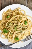 Pesto spaghetti pasta with basil, garlic, pine nuts, olive oil. Vertical. Rustic table photo