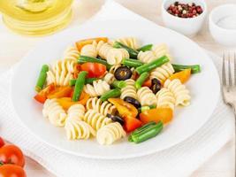 Italian salad with fusilli paste tomatoes, olives, green beans, side view, close up
