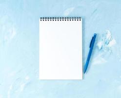 Top view of modern bright blue office desktop with pen or pencil, notepad. Mock up, empty space photo