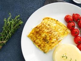 Fish cod baked in oven with mashed potatoes, tomatoes, diet healthy food. Dark gray background photo