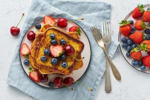 French toasts with berries, brioche breakfast, white background top view photo