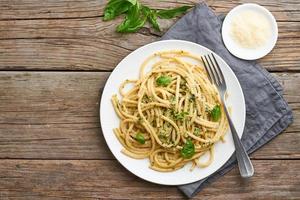 Pesto spaghetti pasta with basil, garlic, pine nuts, olive oil. Copy space. Rustic table photo