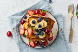 French toasts with berries and banana, brioche breakfast, white background, top view