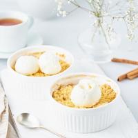 Close up apple crumble with ice cream, spoon with streusel. Side view, vertical photo