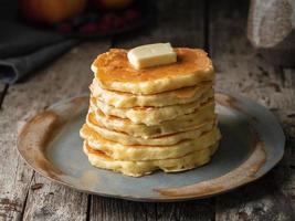 Pancake with butter, close-up. Dark moody old rustic wooden background. photo
