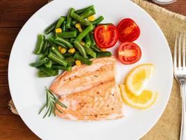 Fish salmon steamed with vegetables. Healthy diet food, dark wooden backdrop photo