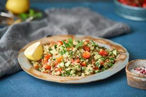 Tabbouleh salad with quinoa. Eastern food with vegetables mix, vegan diet. Side view, old plate photo