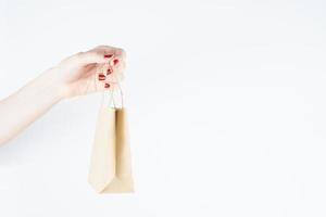 woman holding paper bag on white background, person with red nail polish, mockup design, copy space photo