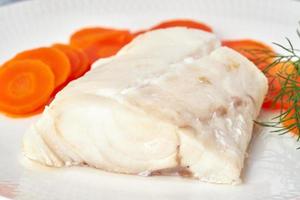 Boiled codfish with carrot and dill on white plate, fodmap dash paleo diet, side view closeup photo