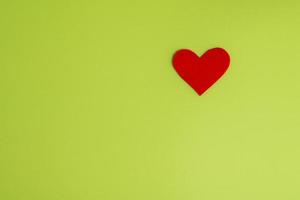 Concept of charity and healthcare donation. Heart symbol of love and romance on green background photo