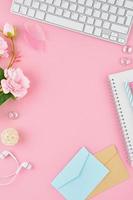 Blank notepad page in bullet journal on bright pink office desktop. Top view of modern bright table with notebook, stationery. Mock up, copy space, concept for diary, vertical photo