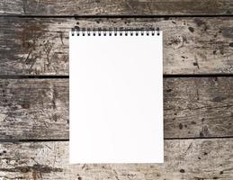 open notepad with clean white page on aged old rustic wooden table, top view photo