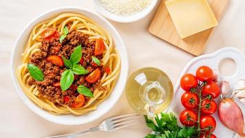 pasta bolognese with tomato sauce, ground minced beef, basil leaves on background photo