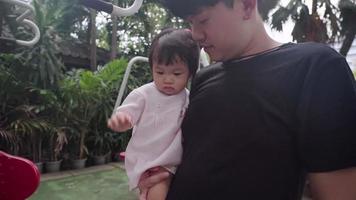 Asian father and his baby girl while taking a walk inside the park, under trees shade, infant child adorable cute, child care parenting, Family mix generation bonding, children innocence curiosity video