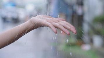 Mädchenhand fängt Regentropfen ein, berührt die Jahreszeit, Regen auf weiblicher Handfläche, Regenzeit-Zeitlupe, auf der Straßenseite, Temperaturänderungen, Luftfeuchtigkeit, Luftkondensation, Wettervorhersage, Regenkatzen und -hunde video