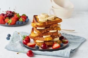 French toasts with berries and banana, brioche breakfast, white background, closeup photo