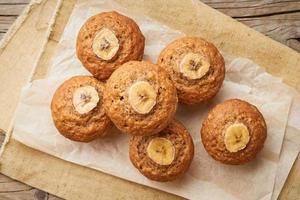 Banana muffin, top view. Cupcakes on old linen napkin, rustic wooden table, breakfast with cake photo