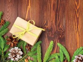 navidad y feliz año nuevo fondo marrón oscuro. caja de regalo de navidad, ramas de abeto, mesa de madera, vista superior, espacio de copia foto