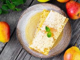 honey in honeycomb, close-up, on brown ceramic plate, on old gray wooden rustic table, top view photo