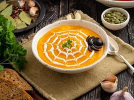 comida divertida para halloween. sopa de puré de calabaza, telaraña, mesa de madera vieja oscura, vista lateral. foto