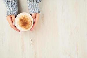 Top view hands holding cup of hot chocolate, cozy sweater, beautiful pink manicure, home style, autumn morning, close up