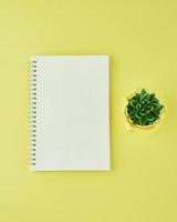Blank notepad page in bullet journal on bright yellow office desktop. Top view of modern bright table with notebook, minimalism. Mock up, copy space, concept for diary photo