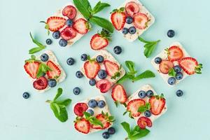 Rice crispbread with berries and fruits colorful concept on turquoise aquamarine background photo