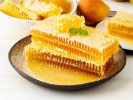 honey in honeycomb, close-up, on brown ceramic plate, on white wooden rustic table, side view photo