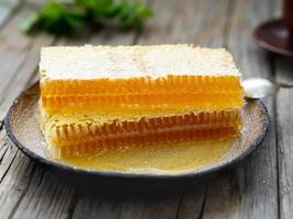 honey in honeycomb, close-up, on white ceramic plate, on wooden rustic table, photo