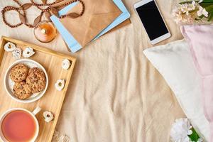 Mockup with women's accessories on bed tea, cookies, pillows, flowers, letter, notebook. photo