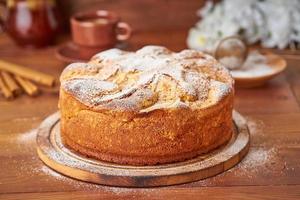 Apple french cake with apples, cinnamon on dark wooden kitchen table, side view