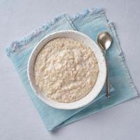 Oatmeal on blue light background. Milk porridge. Vegan food. Top view. Healthy diet breakfast photo