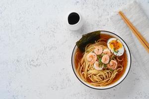 Asian soup with noodles, ramen with shrimps, copy space. White stone table, top view