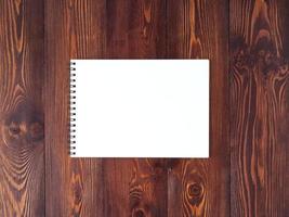 open notepad with spiral on dark brown wooden table, top view photo