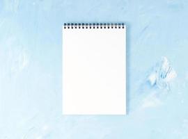 Top view of modern bright blue office desktop with notepad. Mock up, empty space photo