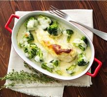 Chicken fillet baked with broccoli in bechamel sauce on dark wooden table. Healthy food photo