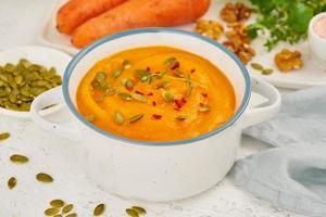 sopa de crema de zanahoria con semillas de calabaza y perejil y nueces, vista lateral sobre fondo claro cerrado