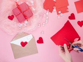 mujer corta corazones de fieltro rojo, artesanía casera para el día de san valentín, creatividad hecha a mano, vista superior foto