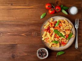 fusilli pasta with tomato sauce, chicken fillet with basil leaves photo