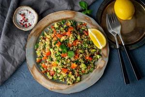 Tabbouleh salad with quinoa. Eastern food with vegetables mix on dark table